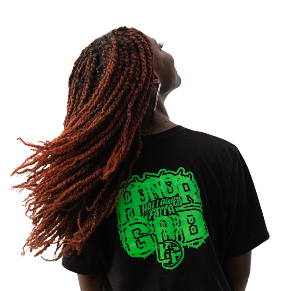 Person wearing a black t-shirt with green graphic design on the back, standing against a white background.